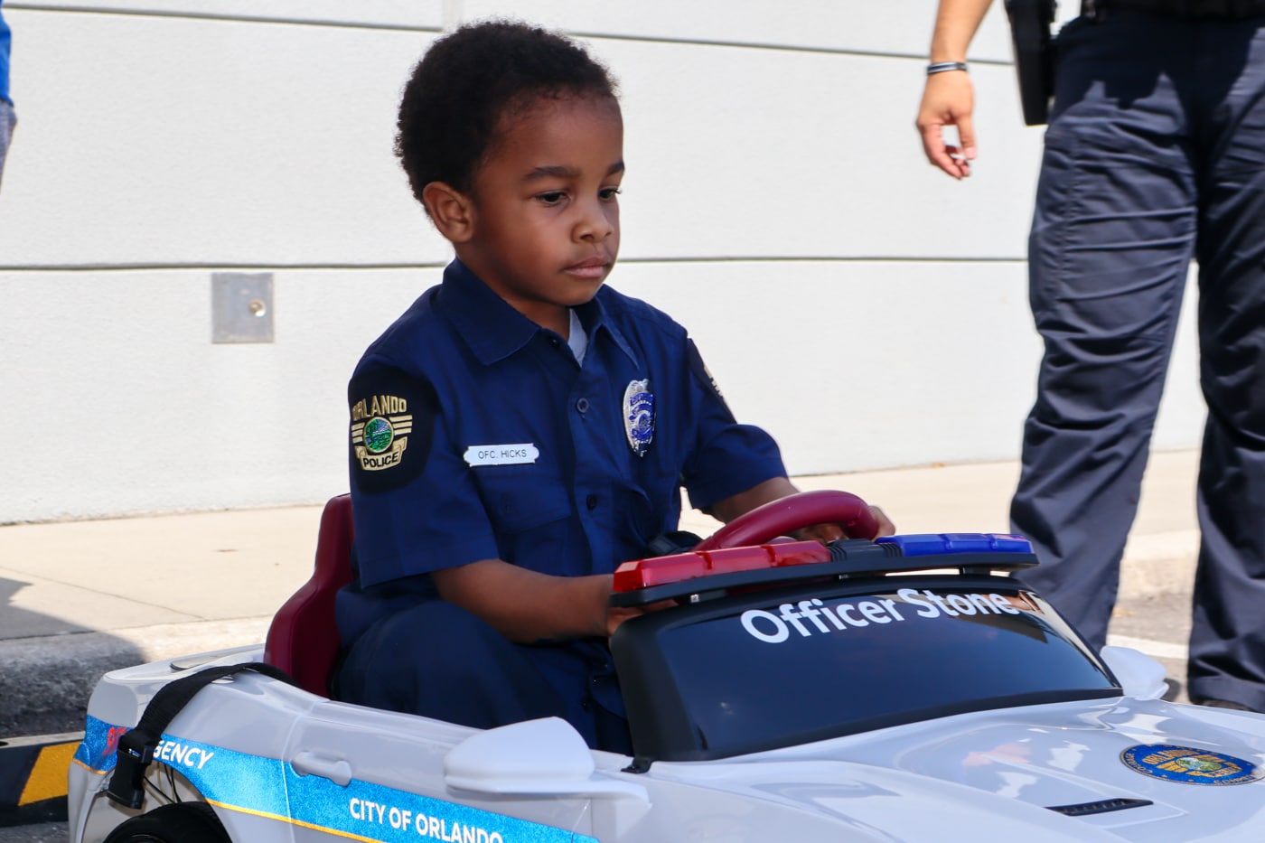Officer Stone in riding in toy police car
